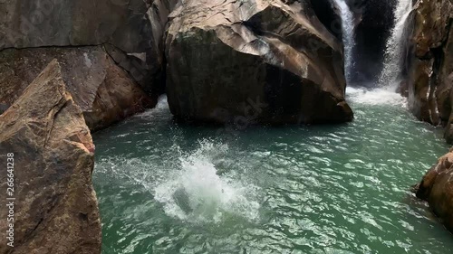 Guy jumping from rocky cliff on waterfall in Vietnam