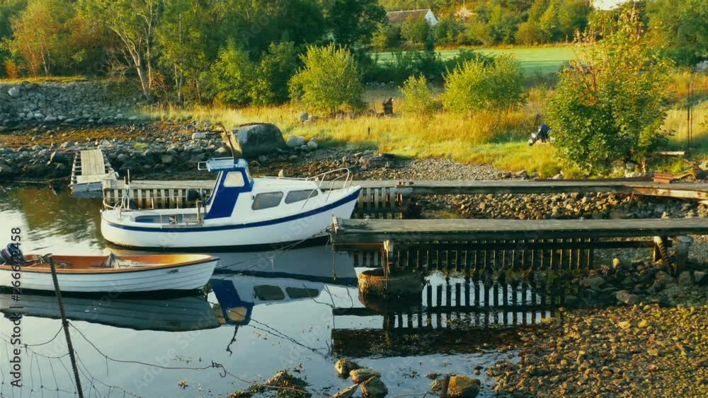 Panning shot of traditional boats in small harbor in Norway, traditional fishing in Scandinavia, wooden piers leading to the water, near Pulpit rock or Prekestolen, small village in background Panning shot of traditional boats in small harbor in Norway, traditional fishing in Scandinavia, wooden piers leading to the water, near Pulpit rock or Prekestolen, small village in background
