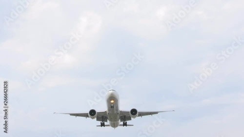 Large passenger airplane landing against beautiful clear sky. Commercial airplane flying directly over camera. photo