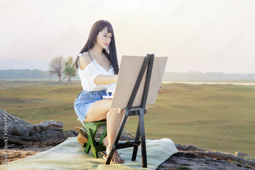 A beautiful young woman sitting in a meadow with sunrise in the background,Beautiful woman at mountain pastures.
