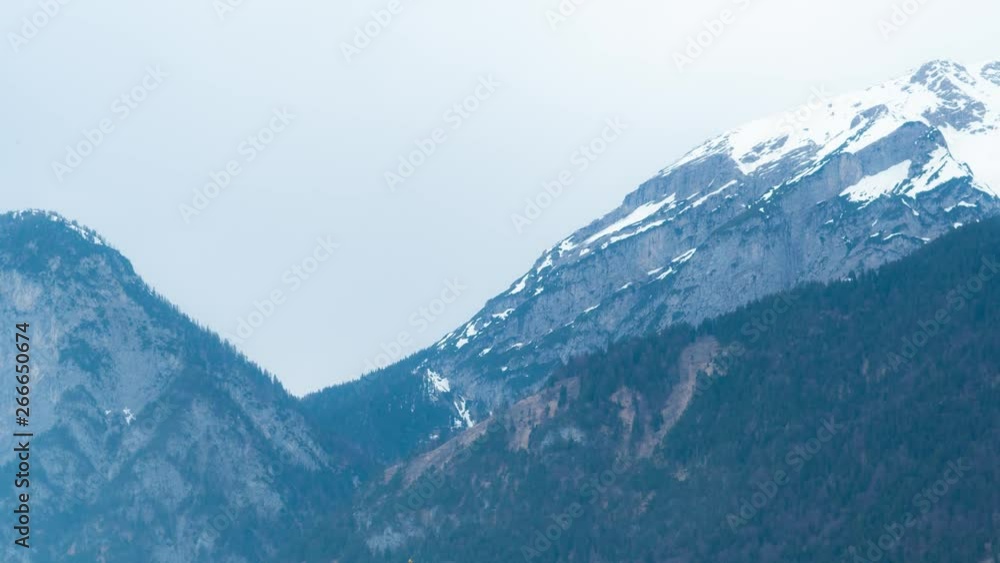 Moody time lapse of mountains at hazy weather. Sun rays. Forest and snow on the top. Moody time lapse of mountains at hazy weather. Sun rays. Forest and snow on the top.