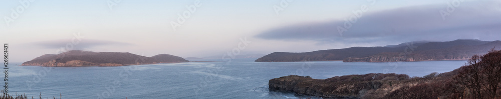 Seascape with capes and the island, over which hung a thunderstorm. Image of landscape and weather phenomena. Panoramic landscape