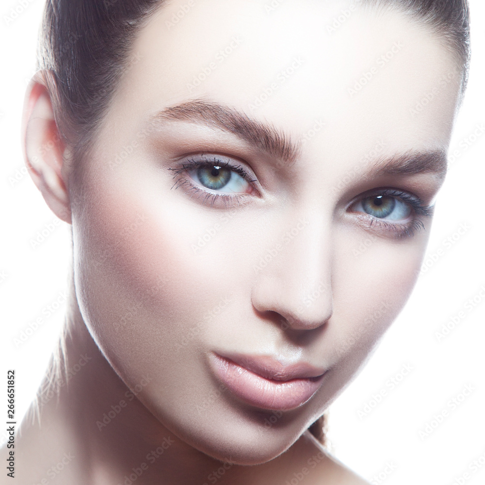 Fototapeta premium Close-up beauty face of sensual young model girl. Perfect skin, looking at camera, blue eyes. Natural nude make-up. Skincare beauty facial treatment, spa, female health concept. White background