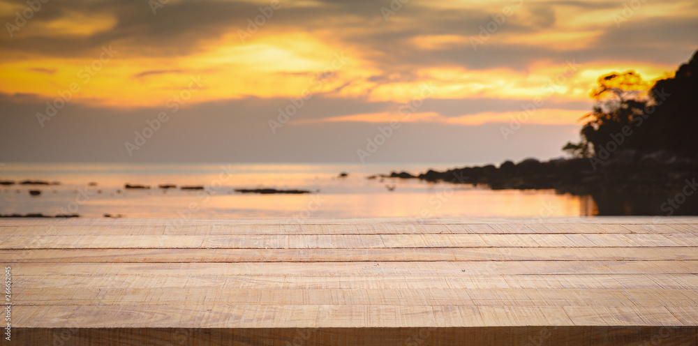 Obraz premium Empty wooden bar counter with blurred sunset beach background.