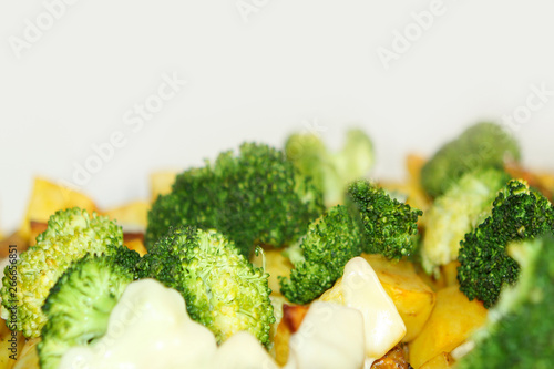 Baked potatoes with cheese, broccoli, mushrooms, turmeric and other spices from the oven close-up.
