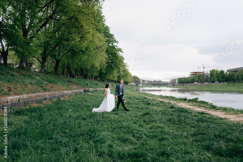 Fototapeta Naklejka Na Ścianę i Meble -  The bride and groom walk on the street. River bank, fresh air