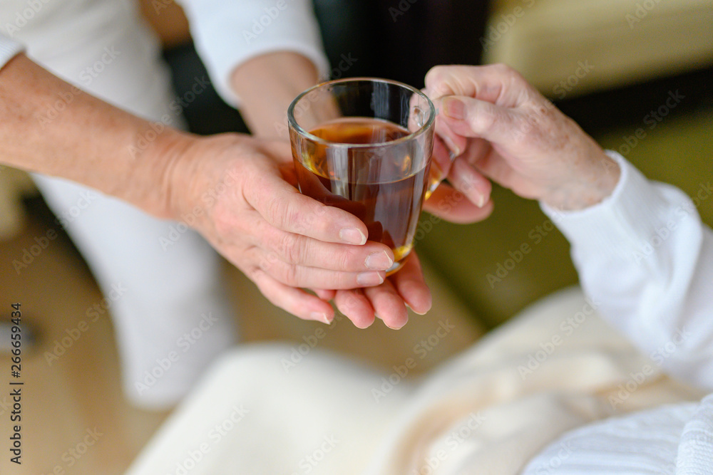 Rentnerin bekommt von der Pflegekraft ein Glas Tee gereicht Rentnerin bekommt von der Pflegekraft ein Glas Tee gereicht