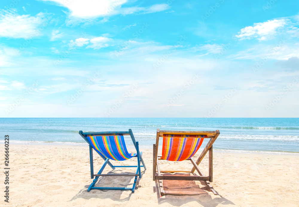 Two beach chairs on white sand, blue sky and summer sea background. Summer concept, holiday, travel, text input area 