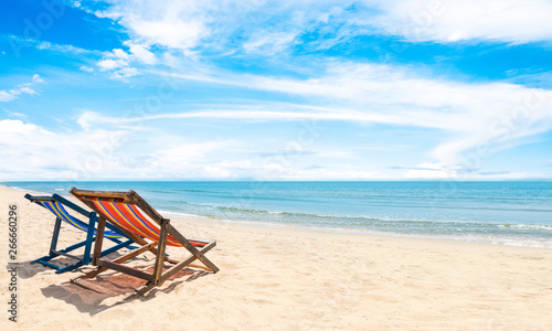 Two beach chairs on white sand, blue sky and summer sea background. Summer concept, holiday, travel, text input area 