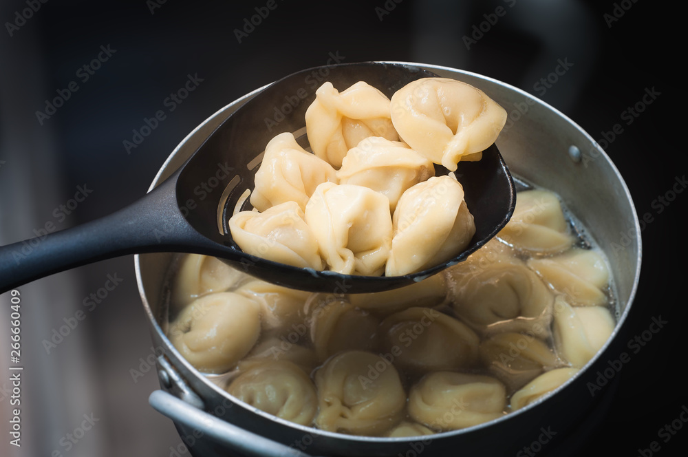 a sieve with ready dumplings above the pan with dumplings with a blurred background ready to eat a sieve with ready dumplings above the pan with dumplings with a blurred background ready to eat
