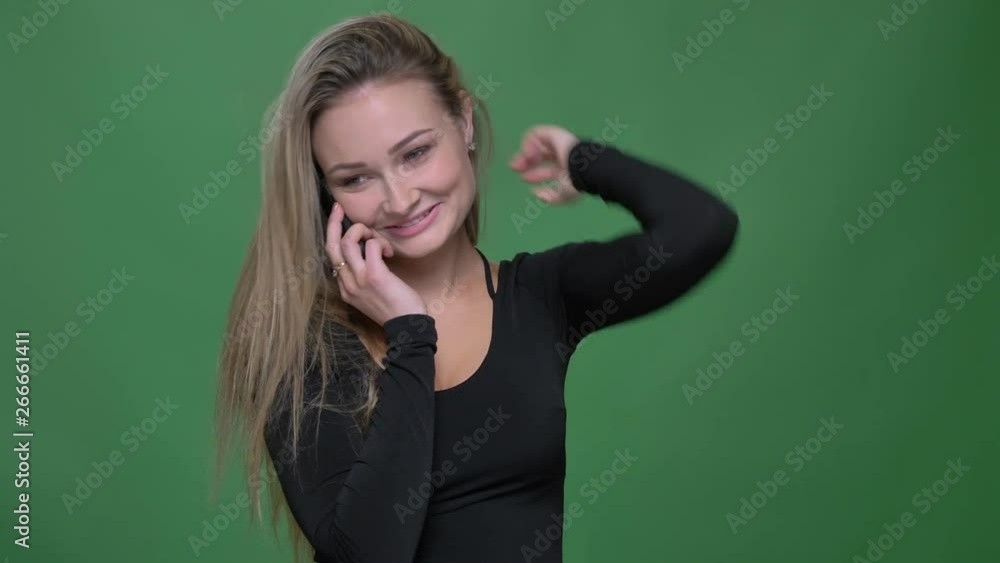 Portrait of young businesswoman in black blouse talking joyfully on smartphone at green background. Portrait of young businesswoman in black blouse talking joyfully on smartphone at green background.