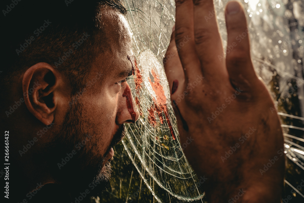 Obraz premium Victim of war. Wounded man victim looking through broken glass. Crime or violence victim. Victim of accident