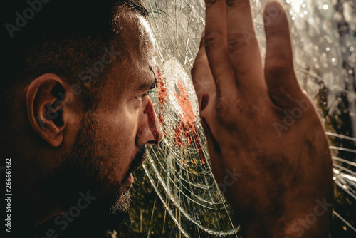Victim of war. Wounded man victim looking through broken glass. Crime or violence victim. Victim of accident