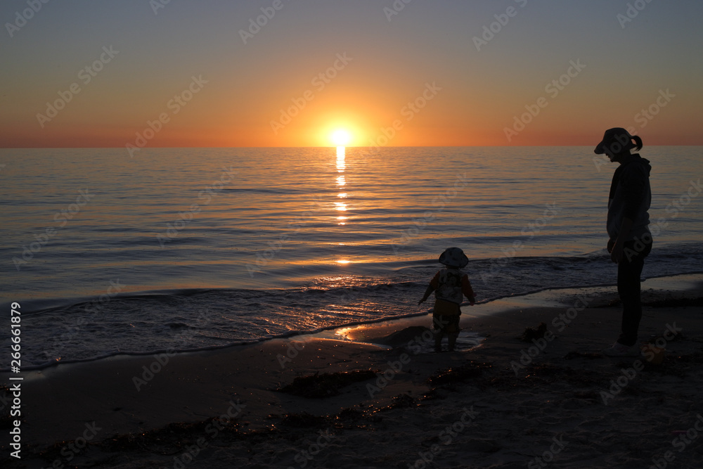 Silhouette of mother and toddler looking at sunset