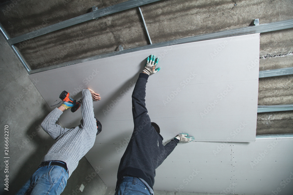 Foto Workers fitting panel into frame of ceiling.