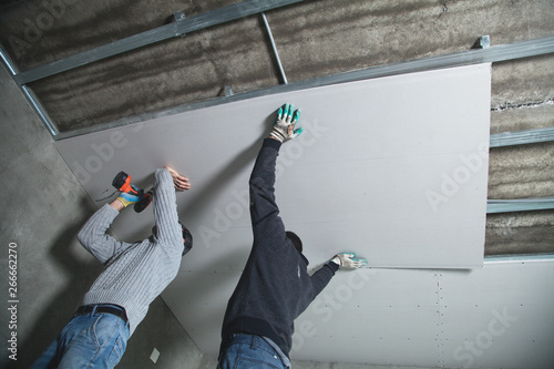 Quadro su tela Workers fitting panel into frame of ceiling.