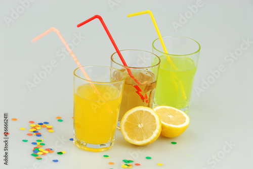 Three mason jar glasses of summer lemonade, and green, orange lemonade drinks, lemon, isolated on a gray background