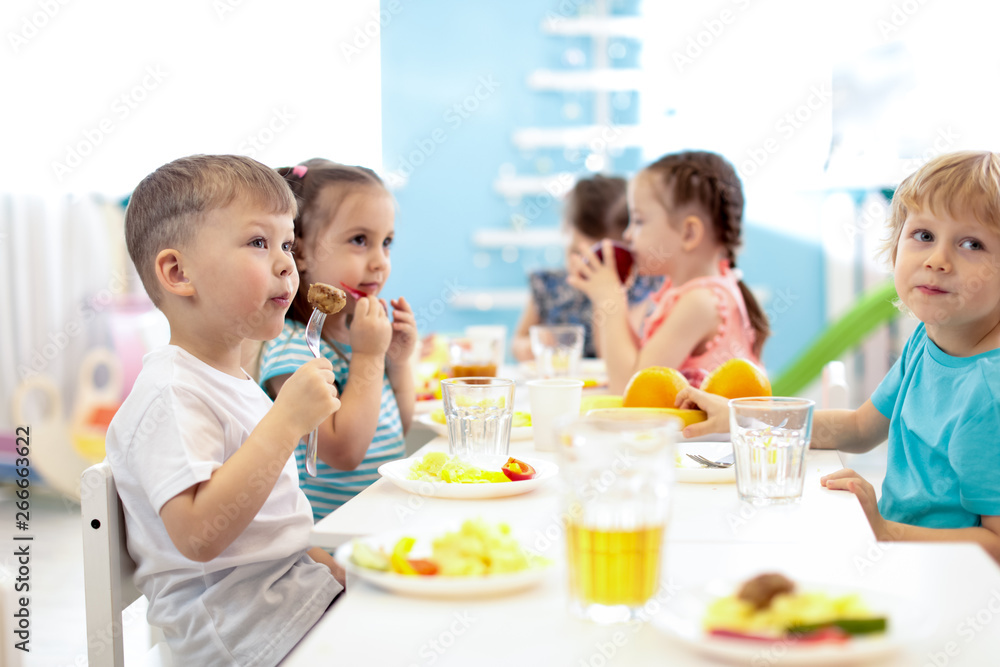 Group of kids have a lunch in day care centre. Children eating healthy food in kindergarten