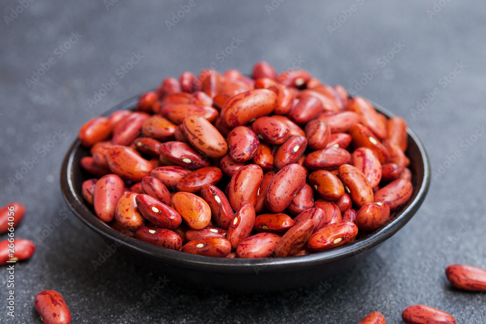 Red kidney beans, lentil in a black bowl on grey stone background. Close up. Red kidney beans, lentil in a black bowl on grey stone background. Close up.