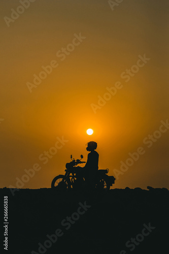 Bike is on the beach with the composition of sun at top photo