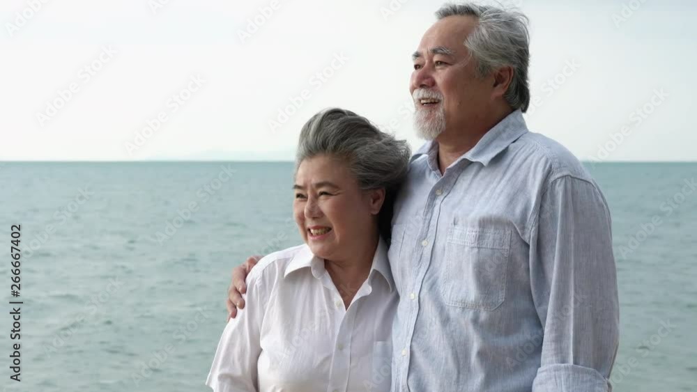 Asian couple senior walking and relax summer on the beach together. Concept of happy family, post retirement, quality life, mental health and positive psychology. Asian couple senior walking and relax summer on the beach together. Concept of happy family, post retirement, quality life, mental health and positive psychology.