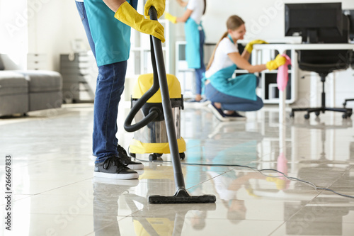 Janitor hoovering floor in office photo