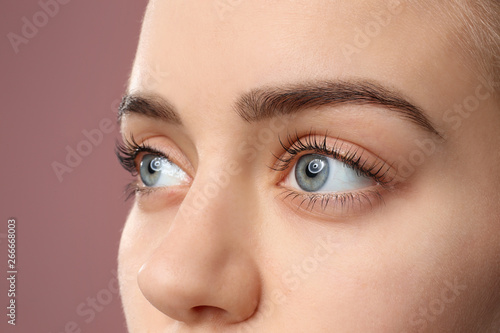 Fototapeta Naklejka Na Ścianę i Meble -  Beautiful young woman with laminated eyelashes on color background, closeup