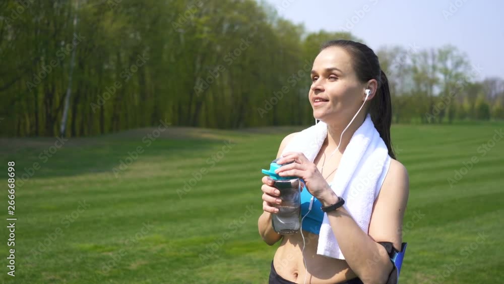 4K. Adult happy fitness woman runner finishes training and drink water 4K. Adult happy fitness woman runner finishes training and drink water