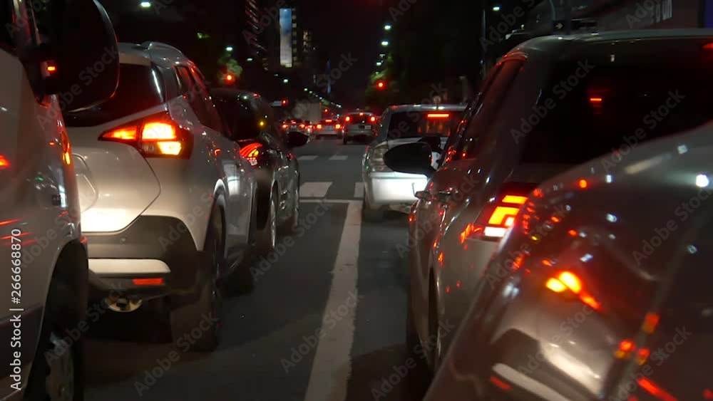 City Night Traffic. Cars waiting for traffic light on avenue. Dusk, early or late. Traffic jam. Many cars with light on. City Night Traffic. Cars waiting for traffic light on avenue. Dusk, early or late. Traffic jam. Many cars with light on.