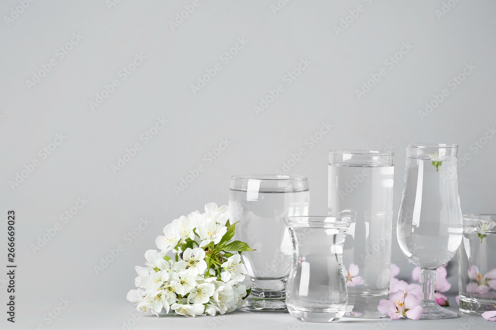 Glasses with water and flowers on table Glasses with water and flowers on table