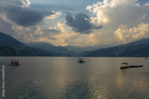 evening lake Phewa with catamarans on the background of a mountain valley in the fog and the evening sky © Pavel