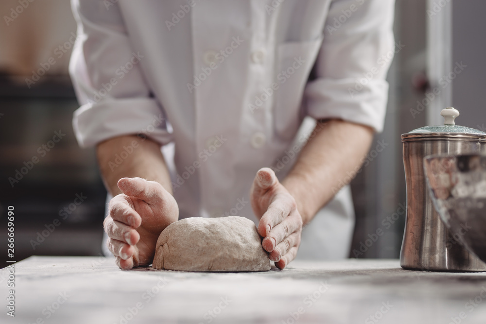Baker kneads dough on the table in the bakery Baker kneads dough on the table in the bakery