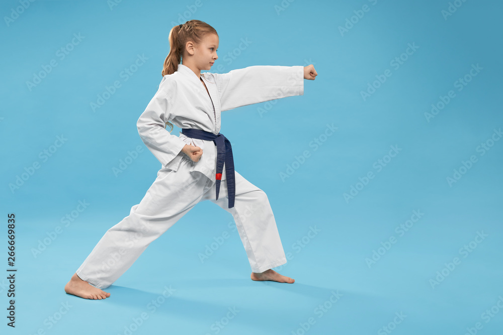 Fototapeta premium Side view of concentrated girl in kimono standing in stance