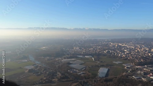 Mountain view of Annemasse and surroundings from the Salève during a sunny day with light fog and bright sun, panning right wide shot photo