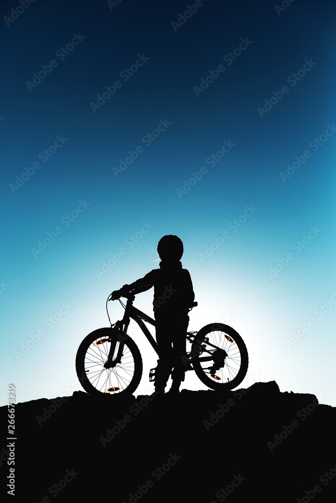 Silhouette of a little girl with a bicycle at sunset Silhouette of a little girl with a bicycle at sunset