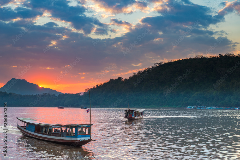 Boats on Mekong River at Luang Prabang Laos, sunset dramatic sky, famous travel destination backpacker in South East Asia