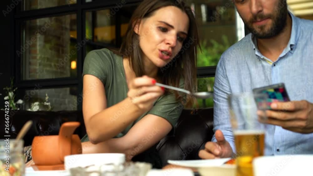 Young couple with smartphone talking during lunch in cafe Young couple with smartphone talking during lunch in cafe