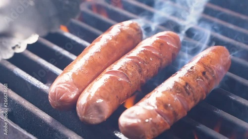 Barbecue Grill Cooking Healthy Low Fat Lean Meat Classic Takeaway Sausages Meal. Slow motion of hot dogs being cooked on an outdoor grill, being turned using a tongs. Making a picnic. Close up