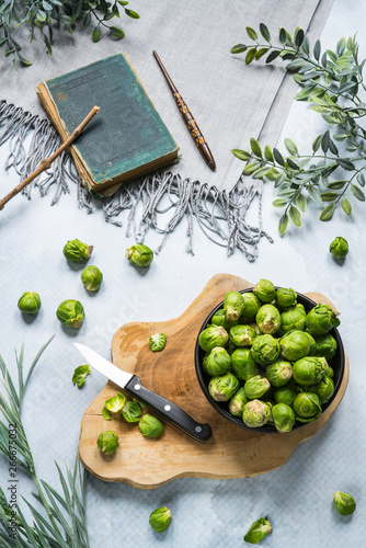 flat lay Brussels sprouts on trunk cutting board, cook book and vintage wooden pen