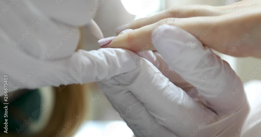 Close-up shot of master uses an electric machine to remove the nail polish during manicure in the salon. Hardware manicure. Concept of body care Close-up shot of master uses an electric machine to remove the nail polish during manicure in the salon. Hardware manicure. Concept of body care