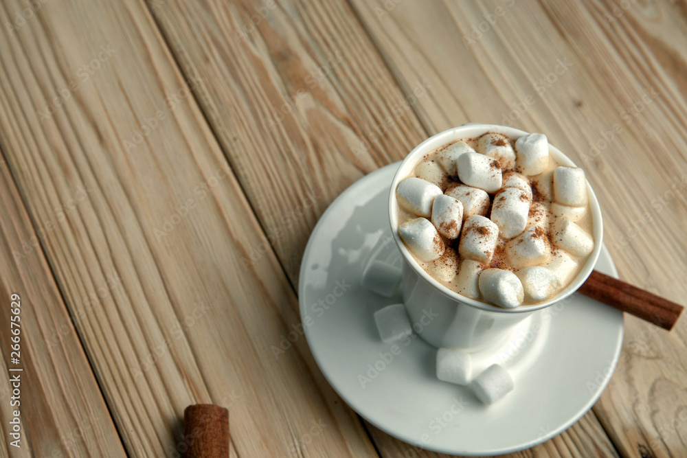 Hot morning coffee with marshmallow and cinnamon on a wooden stand, top view