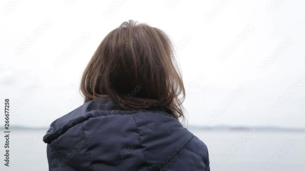 Travel blogger admires nature. Girl sitting on the pier with a view of the lake.