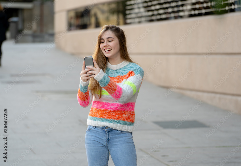 Attractive young woman on smart phone checking social media mobile apps outside city