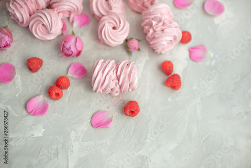 Rose and rose petals, raspberries, homemade pink marshmallows on a concrete background