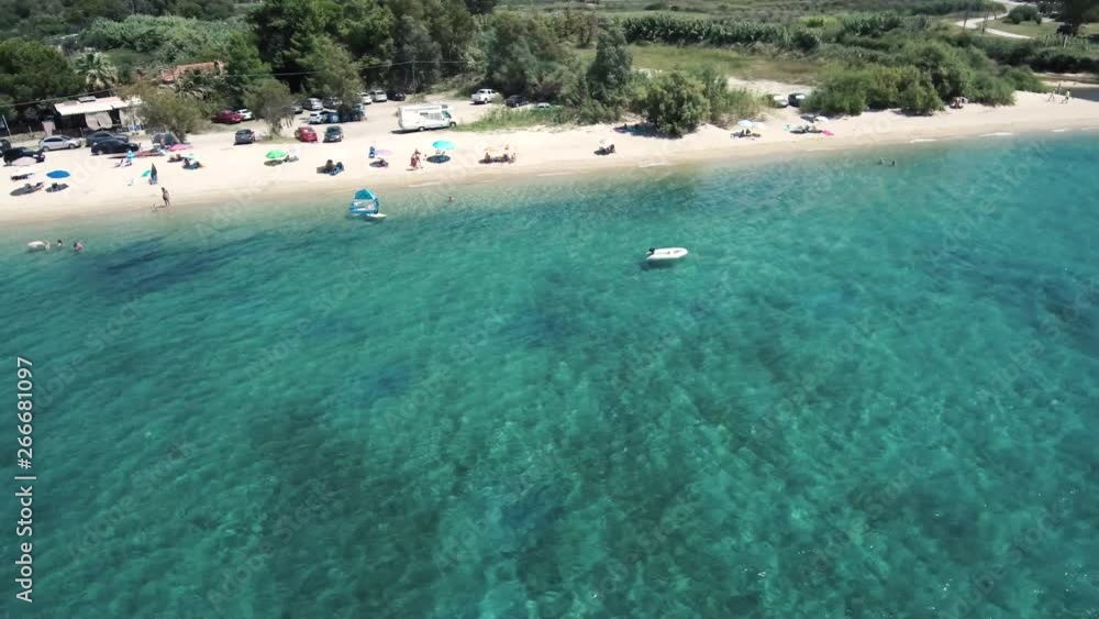 Aerial view of turquoise beach with a small boat, Neos Marmaras Hhalkidiki Greece, circular movement by drone