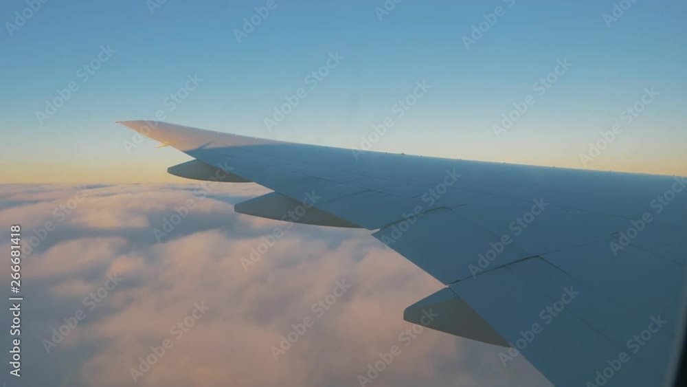 Airplane flight. Wing of an airplane flying above the clouds with sunset sky. View from the window of the plane. Airplane, Aircraft. Traveling by air. Airplane flight. Wing of an airplane flying above the clouds with sunset sky. View from the window of the plane. Airplane, Aircraft. Traveling by air.