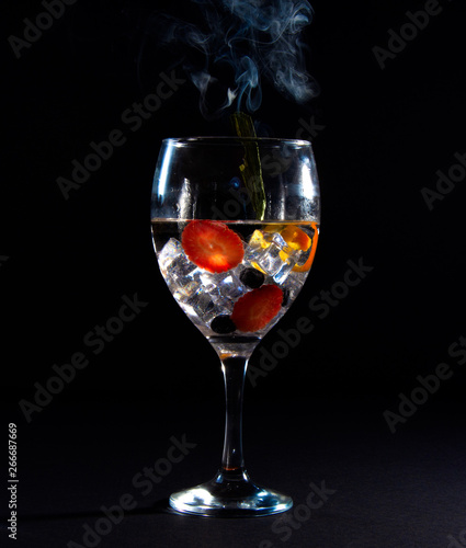 Glass with ice, fruit and smoke
