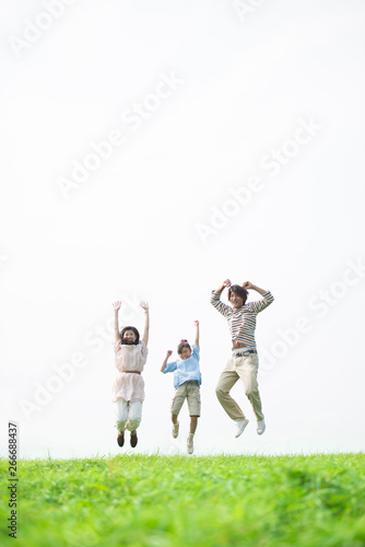 草原でジャンプをする家族