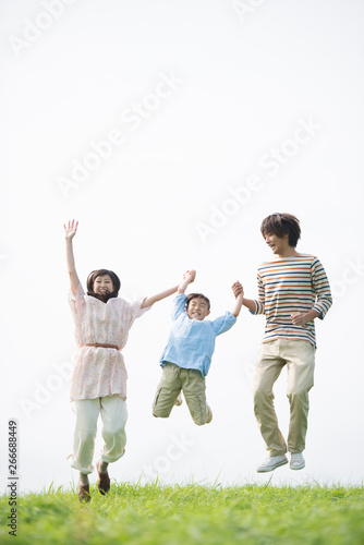草原でジャンプをする家族