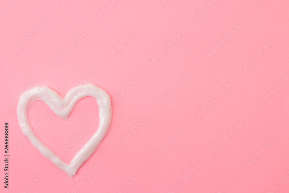 Heart of cream on a bright pink background. Sun protection concept. Ultraviolet protection. Summer. Vacation view from above
